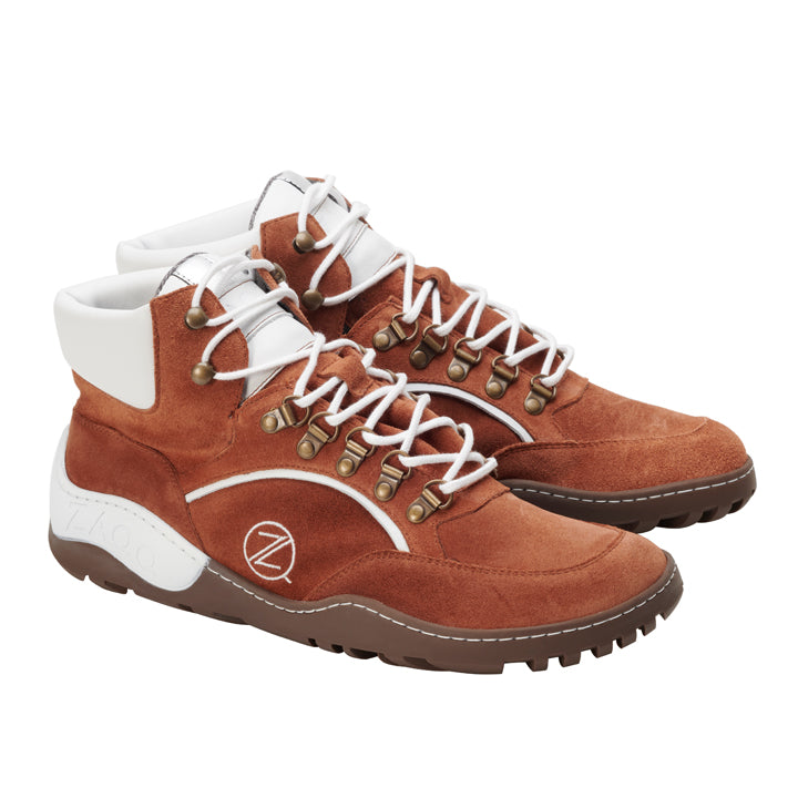 Ein Paar wasserdichte Wanderstiefel TERRAQ Cognac von ZAQQ mit Wildleder-Finish in warmem Braun mit weißen Schnürsenkeln und Akzenten um den Knöchel. Diese Barfußschuhe sind mit robusten braunen Sohlen und metallischen Ösen ausgestattet und somit ideal für Abenteuer im Freien.