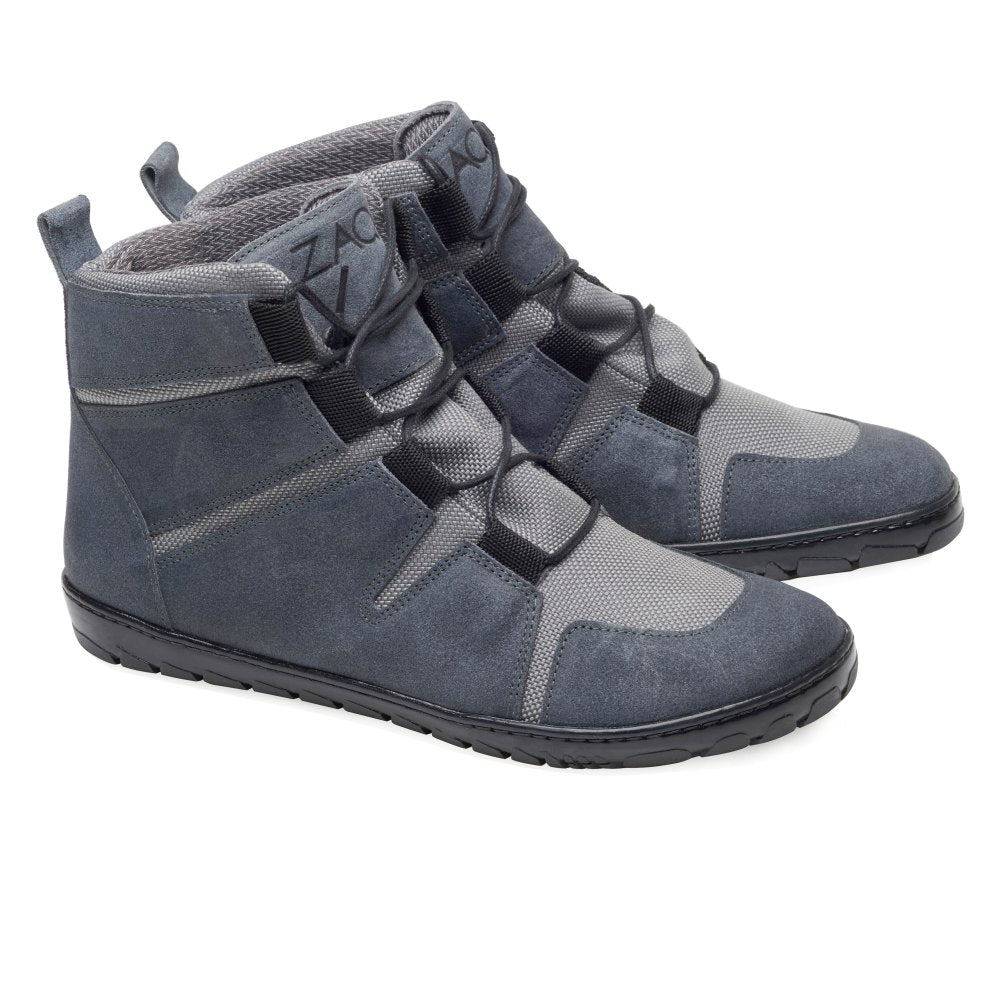 Wir präsentieren die wasserdichten DAQOTA High-Top-Sneaker in Grau von ZAQQ. Diese vielseitigen Schuhe zeichnen sich durch ein elegantes Design mit schwarzen Gummisohlen und Riemen aus. Die kontrastierenden Texturen und die Lasche an der Ferse machen sie ideal für moderne Outdoor-Abenteuer und verbinden Stil mit Funktionalität.