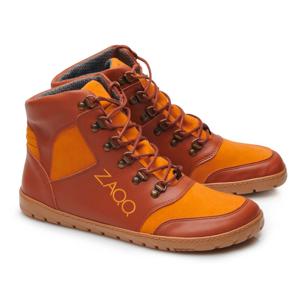 Wir präsentieren den HIQE Vegan Sierra Waterproof von ZAQQ: Diese High-Top-Sneaker präsentieren sich in einem orange-braunen Farbschema mit einem Mix aus Leder- und Stoffmaterialien. Die Schuhe zeigen auffällig ein gelbes ZAQQ-Logo an der Seite, sind mit braunen Schnürsenkeln ausgestattet und sitzen auf hellbraunen Gummisohlen und bieten den Stil eines veganen Wanderschuhs.