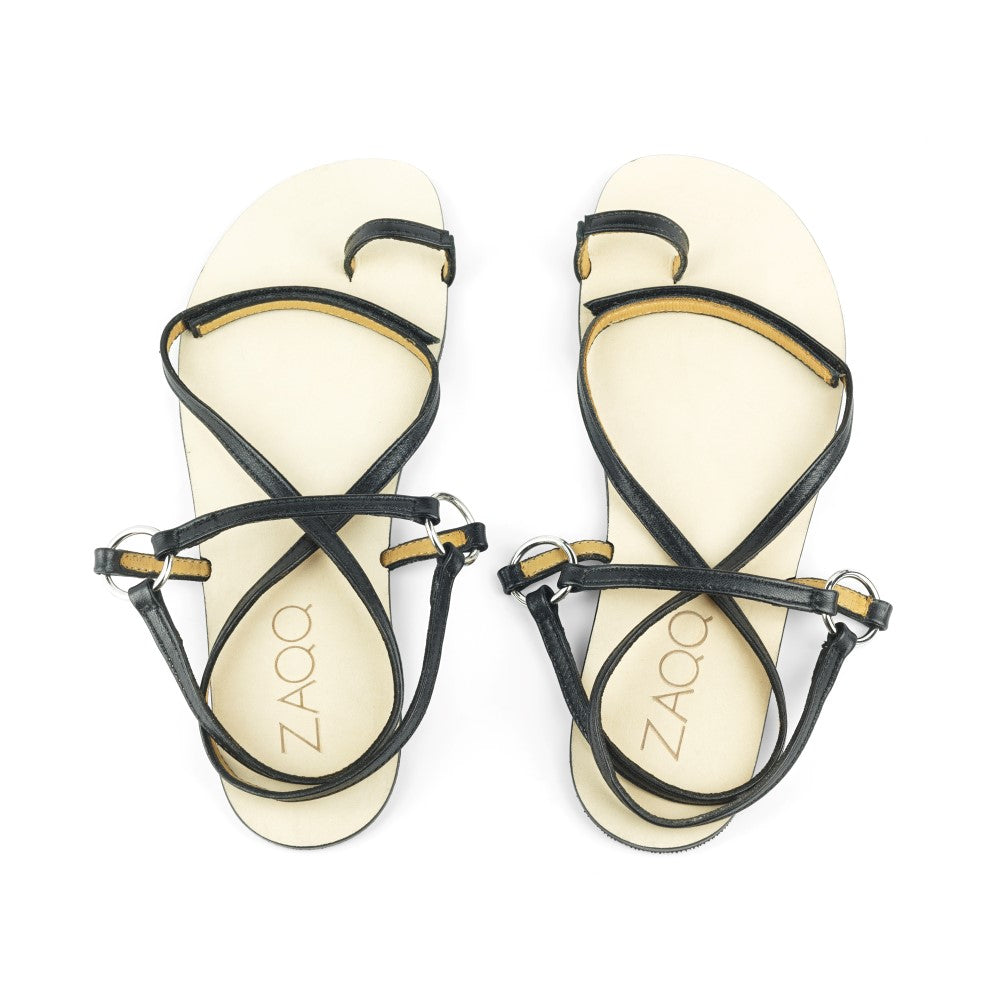 Ein Paar der MINIQ Black-Sandalen von ZAQQ mit dünnen Riemen und Zehenschlaufen, elegant auf weißem Hintergrund präsentiert – ideal, um Ihren Sommerlook zu vervollständigen.