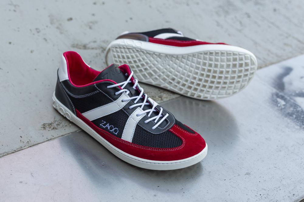 Ein Paar stylische ZAQQ-Sneaker, die OAQLEY Red, mit einem leuchtenden rot-schwarz-weißen Design. Diese Schuhe verfügen über strahlend weiße Schnürsenkel und ein dezentes Branding an der Seite, das sich elegant auf einer strukturierten Betonoberfläche präsentiert.