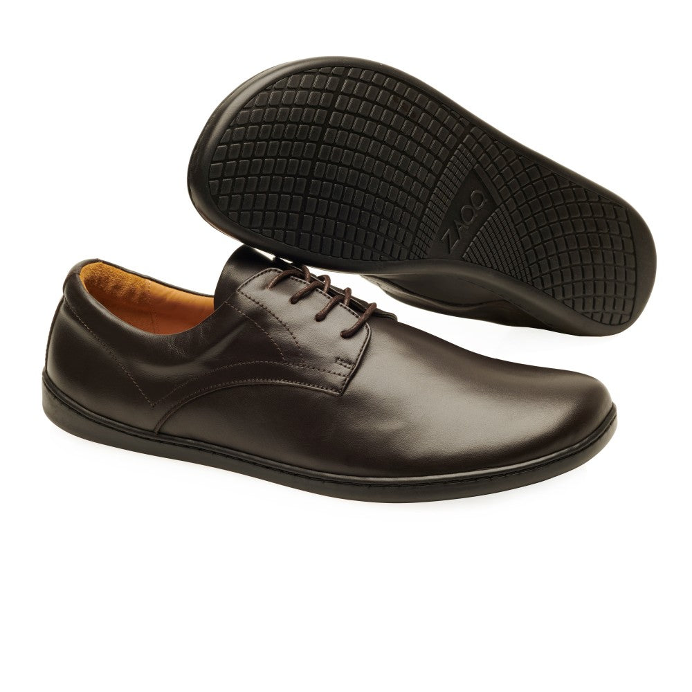 Ein Paar dunkelbraune PEAQ-Schuhe von ZAQQ, ideal für ein Business-Casual-Outfit. Ein Schuh steht aufrecht und zeigt seine glatte Nappalederoberfläche, während der andere umgedreht ist und die strukturierte Sohle freigibt.