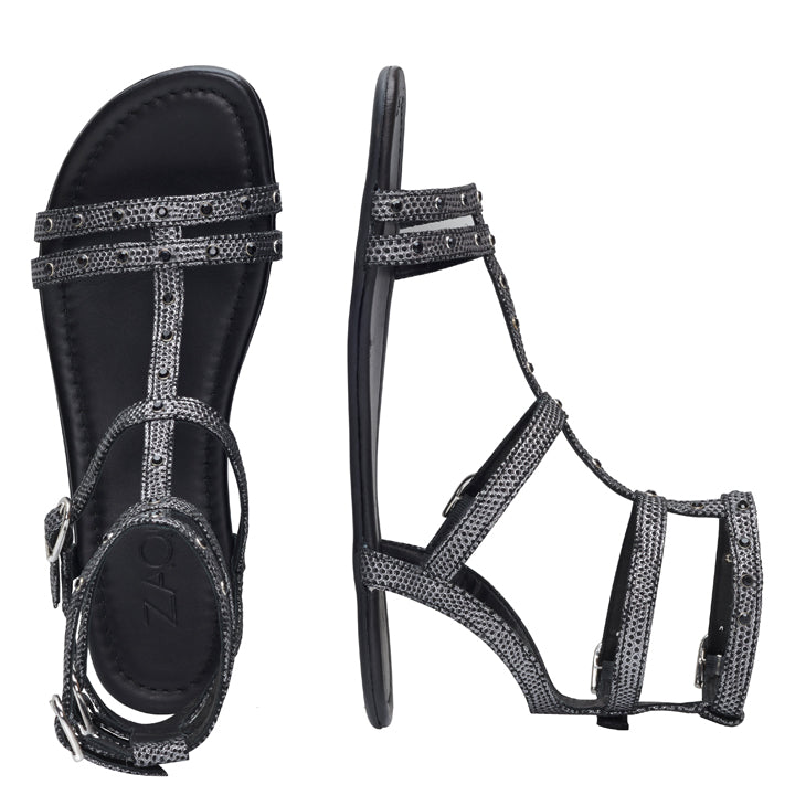 Entdecken Sie die ideale Kombination aus Stil und Komfort mit den QUBA Black Silver-Sandalen von ZAQQ. Diese Barfußsandalen zeigen ein atemberaubendes silbernes Schlangenhautmuster und mehrere Riemen für Knöchel und Zehen. Nebeneinander präsentiert, zeigt eine Sandale ihre Draufsicht, während die andere ihr schlankes Profil hervorhebt.