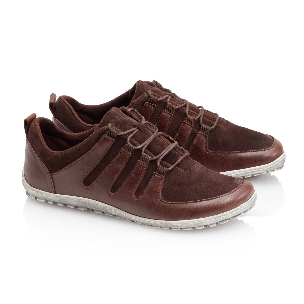 Wir präsentieren die SHOQQ Dark Brown Sneaker von ZAQQ, eine schicke Kombination aus braunem Leder und Wildleder, ergänzt durch weiße Gummisohlen. Diese lässigen Barfußschuh-Sneaker verfügen über ein Schnürdesign und werden kunstvoll vor einem sauberen weißen Hintergrund in Szene gesetzt.