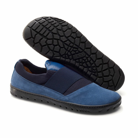 Wir präsentieren den ZAQQ QENT Blue: ein elegantes Paar Slipper mit weichem Obermaterial aus Stoff und einem elastischen Riemen an der Oberseite. Sie verfügen über strukturierte schwarze Sohlen für besseren Halt. Mit seinem sportlichen Schlupfschuh-Design unterstreicht ein Schuh die Atmungsaktivität durch sein Profilmuster, während der andere ein elegantes Seitenprofil aufweist.