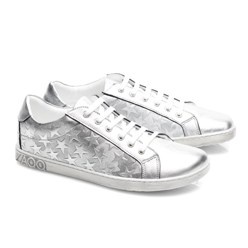 Die SLOQ Stars Silver-Sneaker von ZAQQ haben weiße Schnürsenkel und Sternmuster an den Seiten, ergänzt durch eine weiße Sohle mit VAOO-Prägung an der Ferse. Diese Schuhe zeichnen sich durch ein schlankes und modernes Design mit einem glänzenden Metallic-Finish aus.